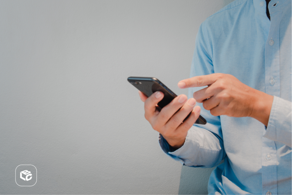 Homem de camisa azul usando smartphone com a mão.