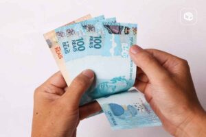 Mãos segurando notas de 100 reais do Real brasileiro.